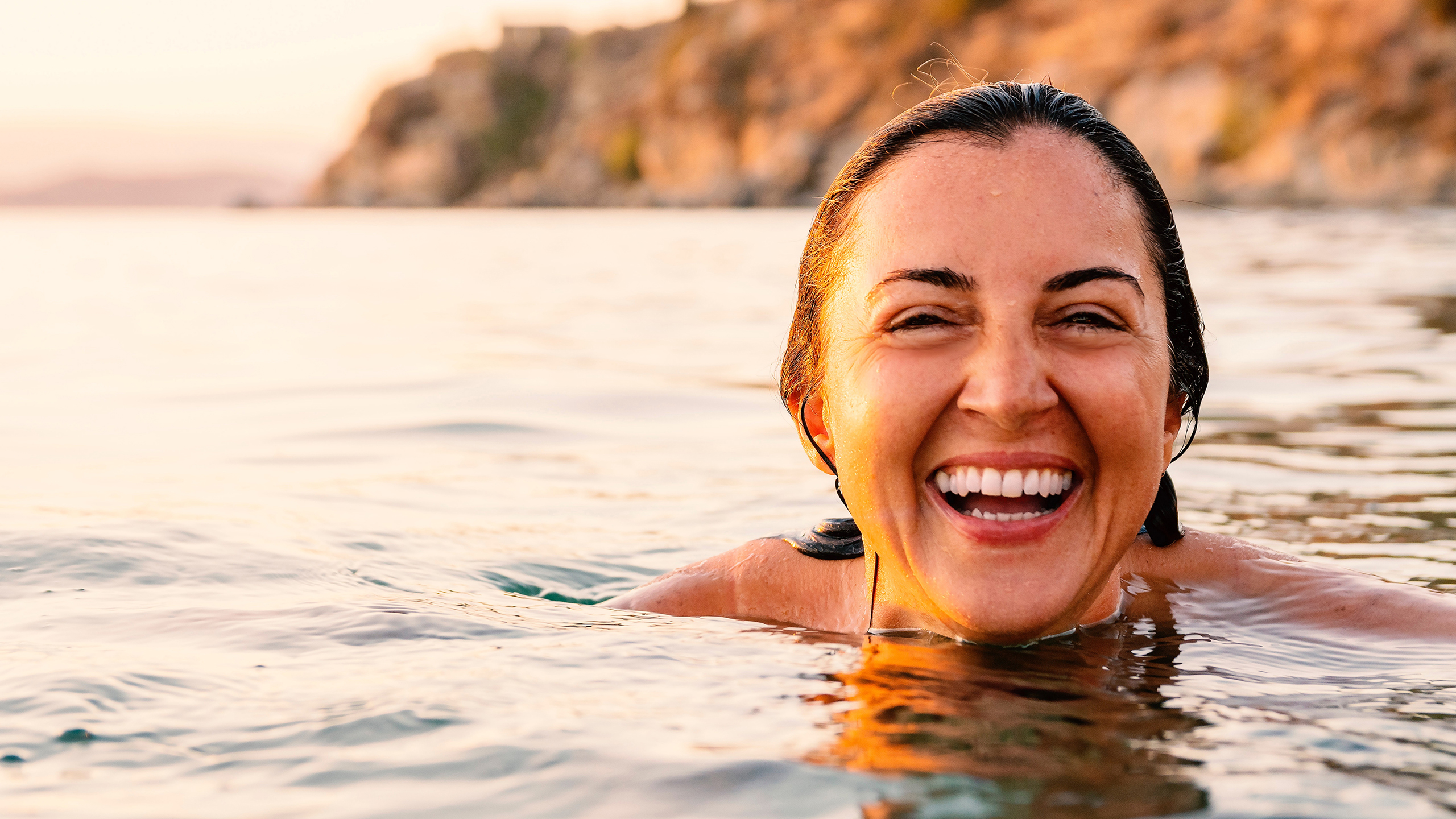 Breast Cancer UK brand hero – a happy woman swimming in the wild